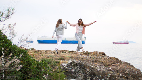 Two young women dancing on the rocky shore