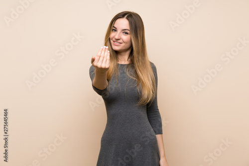 Young woman over isolated background inviting to come with hand. Happy that you came