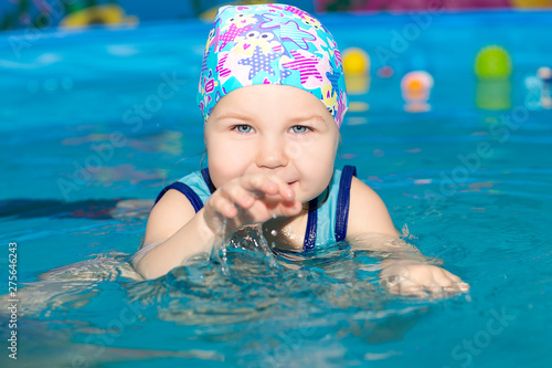 the little girl is engaged plavany, in a blue bathing suit and a hat for swimming
