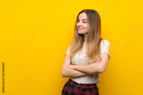 Young woman over isolated yellow wall looking to the side