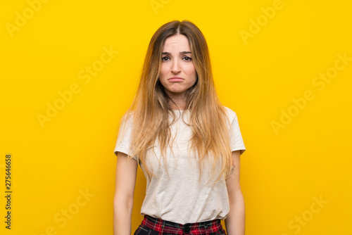 Young woman over isolated yellow wall sad