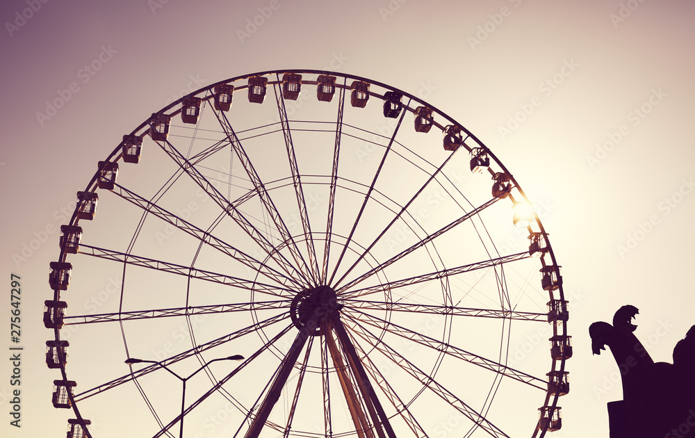 Silhouette of a Ferris wheel at sunset, color toning applied.