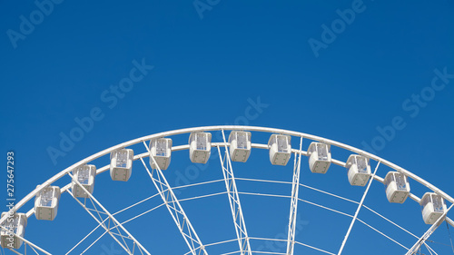 Panoramic view of a Ferris wheel against the blue sky.