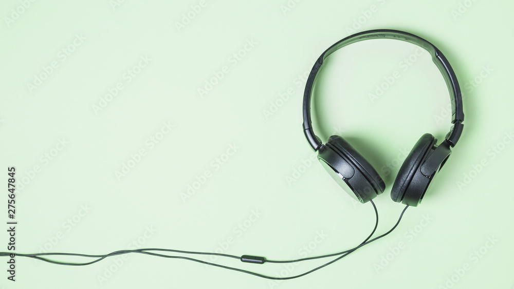 Panoramic view of black headphone on turquoise background Panoramic view of black headphone on turquoise background