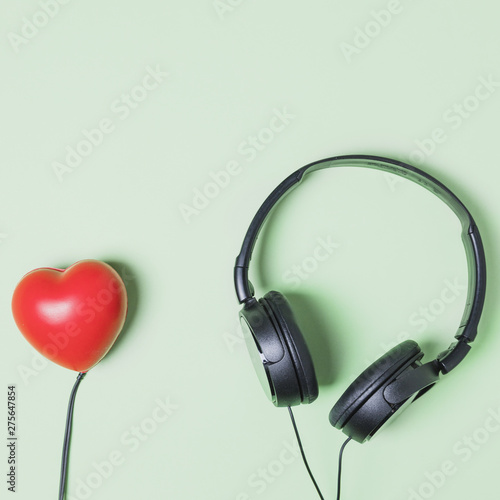 Red heart shape connected to headphone on turquoise background