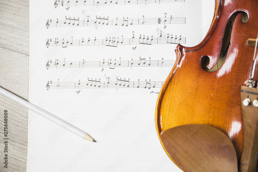 Naklejka premium Pencil and violin over the musical note on table