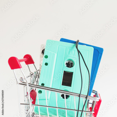 Turquoise and blue cassette tapes in shopping trolley against white backdrop