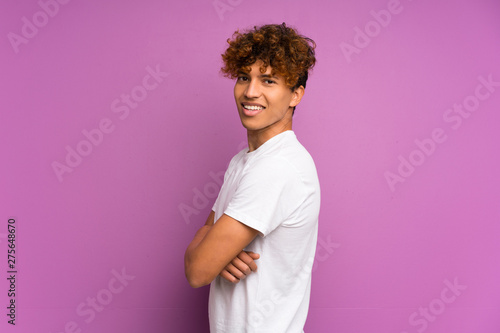 Young african american man over isolated purple wall with arms crossed and looking forward