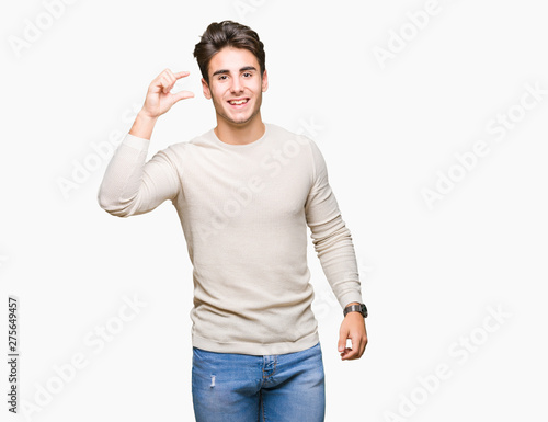 Young handsome man over isolated background smiling and confident gesturing with hand doing size sign with fingers while looking and the camera. Measure concept.