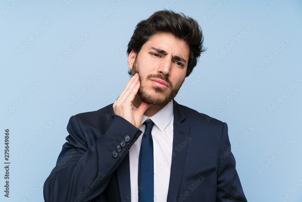 Businessman over isolated blue wall with toothache Businessman over isolated blue wall with toothache