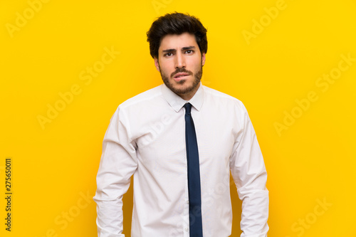 Businessman on isolated yellow background having doubts and with confuse face expression