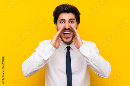 Businessman on isolated yellow background shouting with mouth wide open © luismolinero