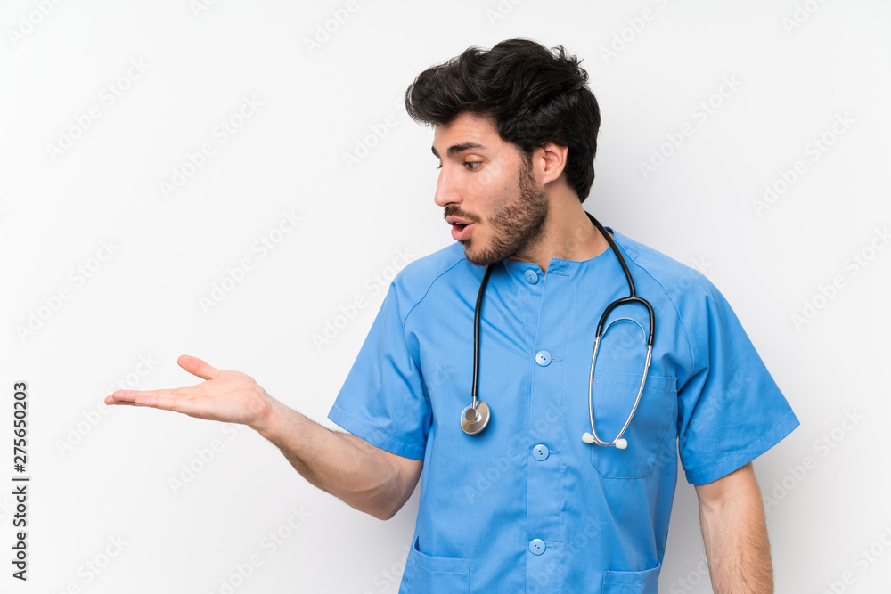 Surgeon doctor man over isolated white wall holding copyspace imaginary on the palm Surgeon doctor man over isolated white wall holding copyspace imaginary on the palm