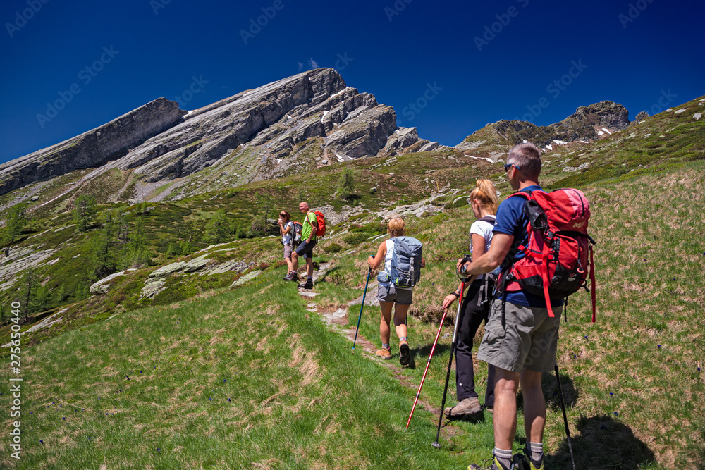 Hikers in sight of the rock slabs of the Pioda di Crana.