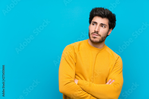 Handsome over isolated blue wall with confuse face expression