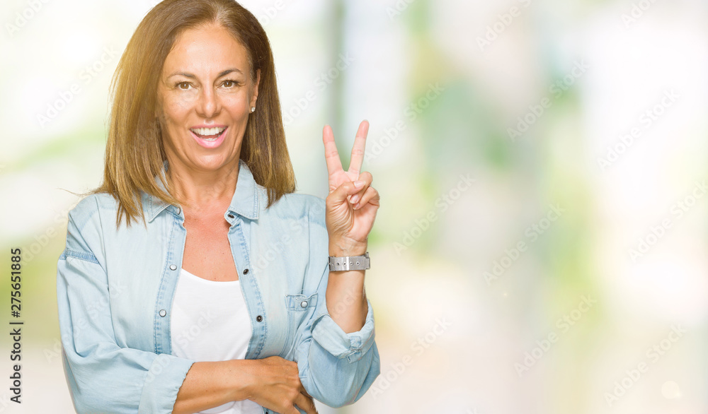 Middle age adult woman wearing casual denim shirt over isolated background smiling with happy face winking at the camera doing victory sign. Number two. Middle age adult woman wearing casual denim shirt over isolated background smiling with happy face winking at the camera doing victory sign. Number two.