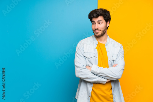 Handsome over isolated colorful background making doubts gesture looking side
