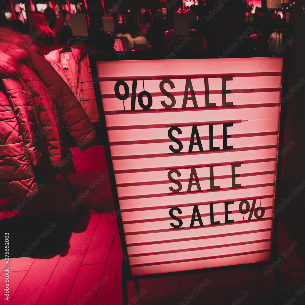 Stylish vintage sign. SALE in a showcase of a clothing store. Beautiful red lights