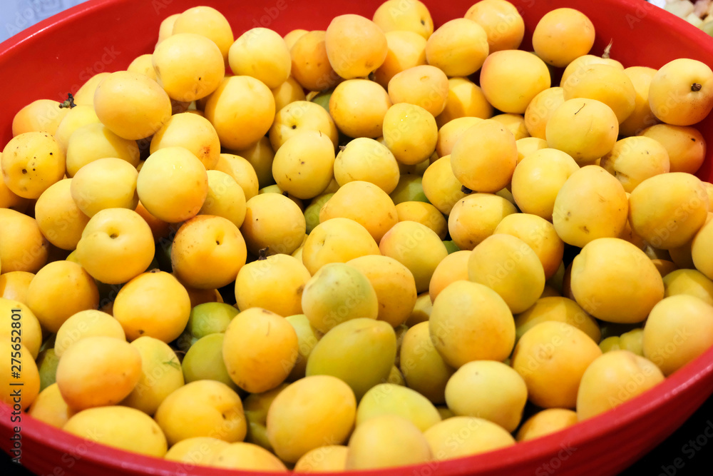 Unripe yellow and green apricots in a basket on the table. Cultivation and care of fruit. Cultivation of gardens and productivity. Unripe yellow and green apricots in a basket on the table. Cultivation and care of fruit. Cultivation of gardens and productivity.