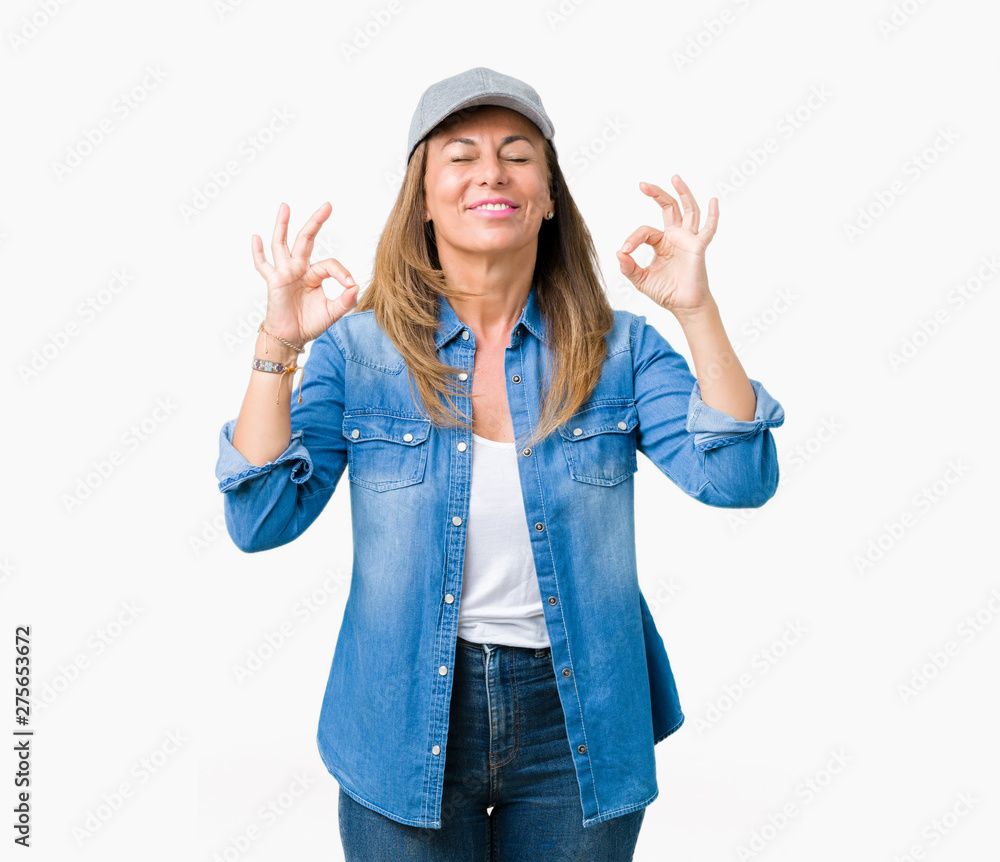 Beautiful middle age woman wearing sport cap over isolated background relax and smiling with eyes closed doing meditation gesture with fingers. Yoga concept. Beautiful middle age woman wearing sport cap over isolated background relax and smiling with eyes closed doing meditation gesture with fingers. Yoga concept.