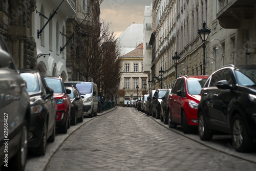 Cars parked in line on both sides of old city street 