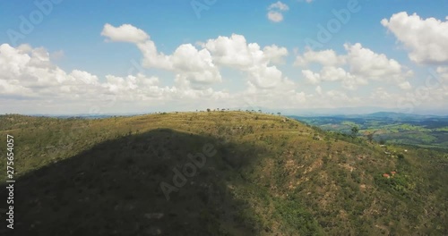 Aerial flight over the top of a hill revealing a green valley near Sao Thome das Letras in Brazil photo