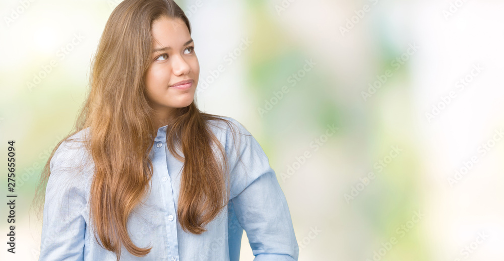 Young beautiful brunette business woman over isolated background looking away to side with smile on face, natural expression. Laughing confident.