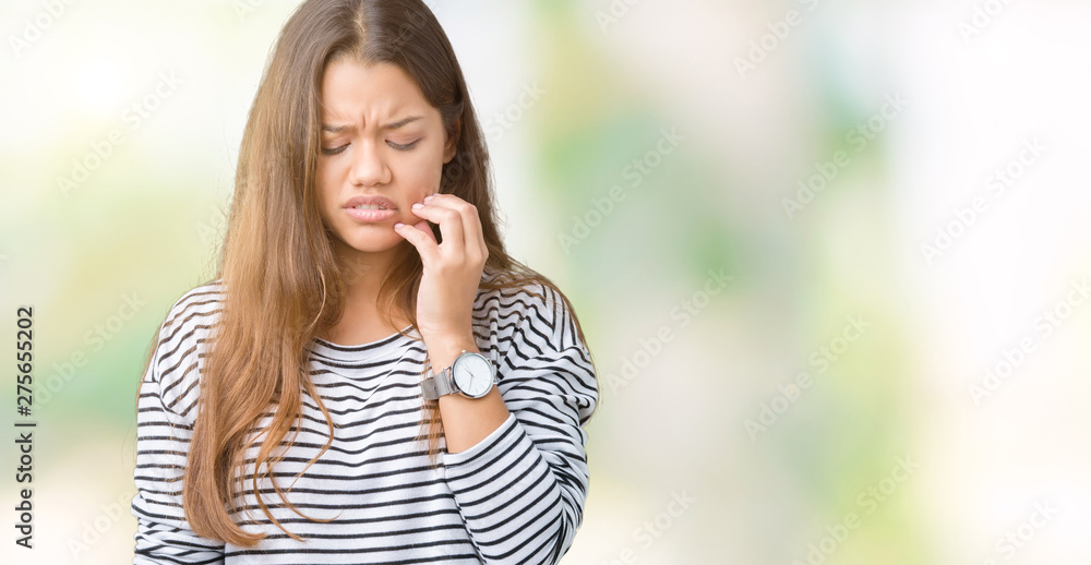 Young beautiful brunette woman wearing stripes sweater over isolated background touching mouth with hand with painful expression because of toothache or dental illness on teeth. Dentist concept. Young beautiful brunette woman wearing stripes sweater over isolated background touching mouth with hand with painful expression because of toothache or dental illness on teeth. Dentist concept.