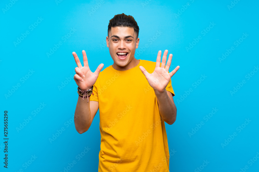 Young man with yellow shirt over isolated blue background counting eight with fingers Young man with yellow shirt over isolated blue background counting eight with fingers
