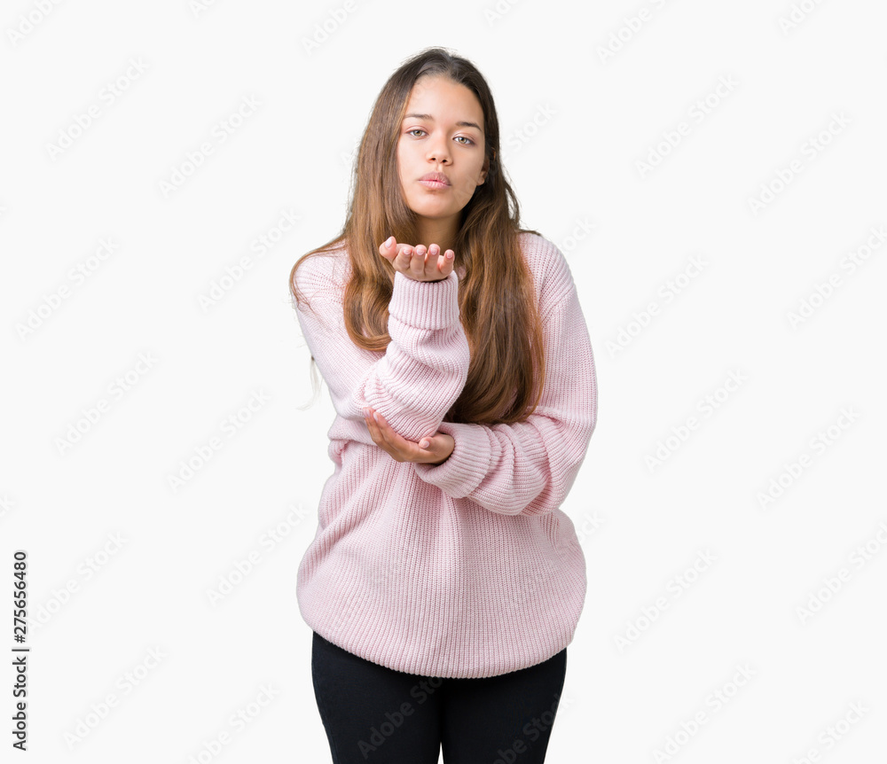 Young beautiful brunette woman wearing pink winter sweater over isolated background looking at the camera blowing a kiss with hand on air being lovely and sexy. Love expression. Young beautiful brunette woman wearing pink winter sweater over isolated background looking at the camera blowing a kiss with hand on air being lovely and sexy. Love expression.