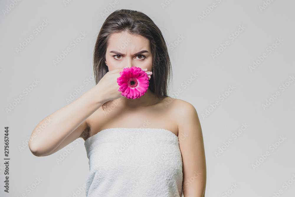 Portrait of beautiful young woman looking at camera with a pink flower. Isolated on white background. Skin care and beauty concept. Portrait of beautiful young woman looking at camera with a pink flower. Isolated on white background. Skin care and beauty concept.