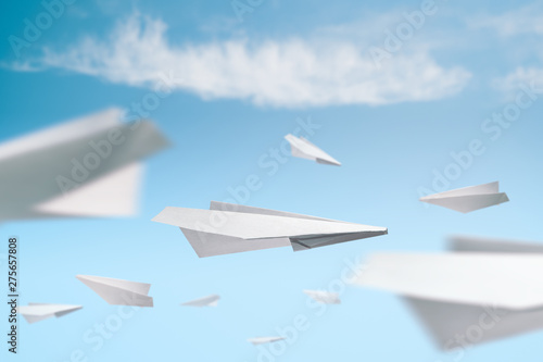 Several flying origami paper planes in a blue sky