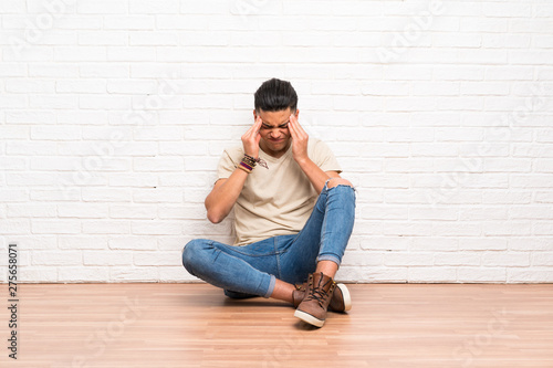 Young man sitting on the floor unhappy and frustrated with something. Negative facial expression