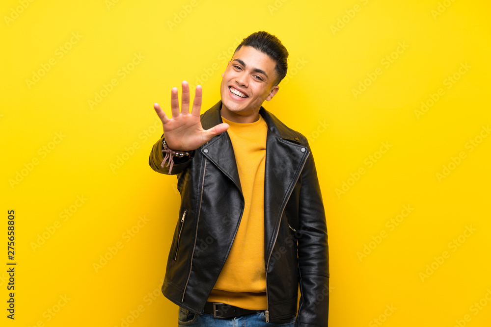 Young man over isolated yellow background counting five with fingers Young man over isolated yellow background counting five with fingers
