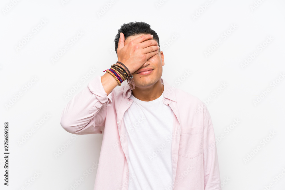 Young man over isolated white wall covering eyes by hands Young man over isolated white wall covering eyes by hands