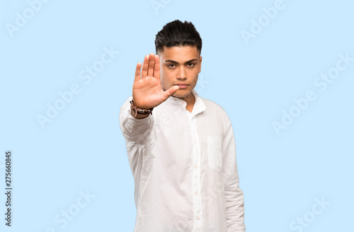 Young man making stop gesture on colorful background