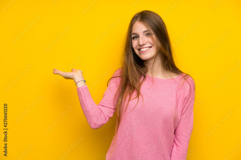 Young woman with long hair over isolated yellow wall holding copyspace imaginary on the palm to insert an ad Young woman with long hair over isolated yellow wall holding copyspace imaginary on the palm to insert an ad
