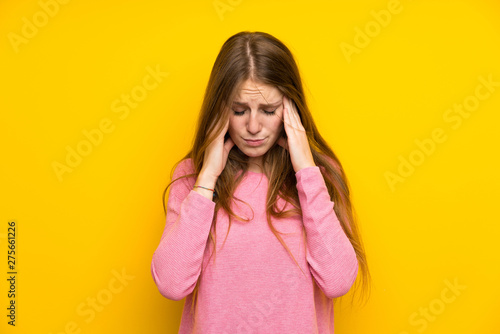 Young woman with long hair over isolated yellow wall with headache