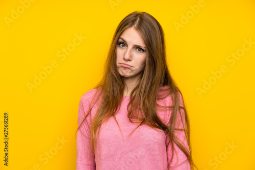 Young woman with long hair over isolated yellow wall with sad and depressed expression © luismolinero