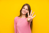 Young woman with long hair over isolated yellow wall happy and counting four with fingers