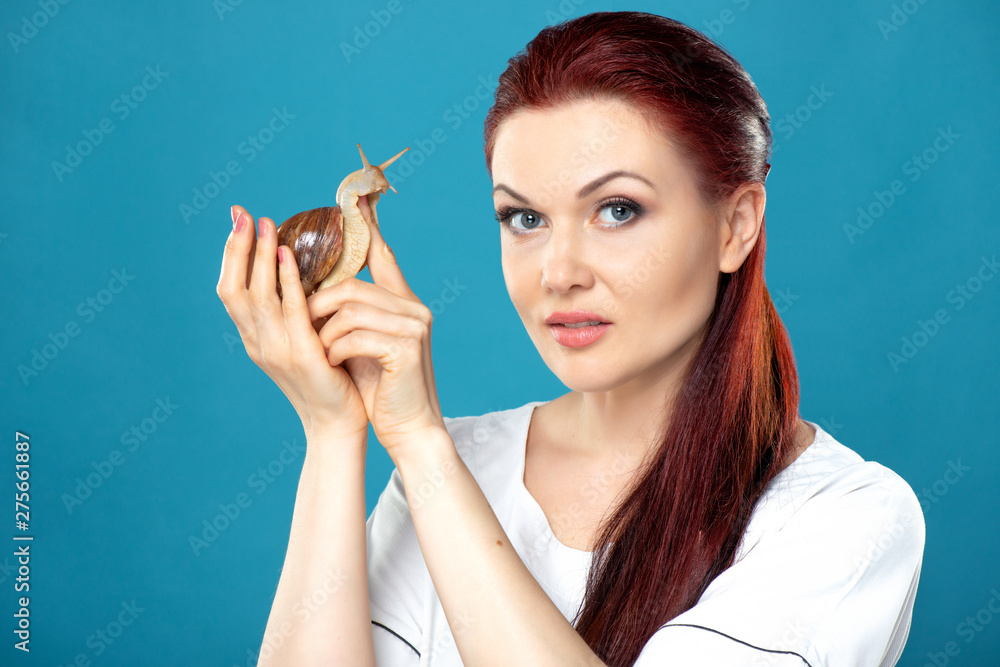 Obraz premium Beautiful female doctor cosmetologist with Akhatina snail in her hands offers collagen mask, snail mucus, skin rejuvenation procedure