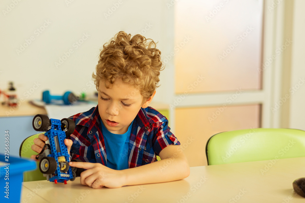 Naklejka premium Nice serious boy holding a constructor car