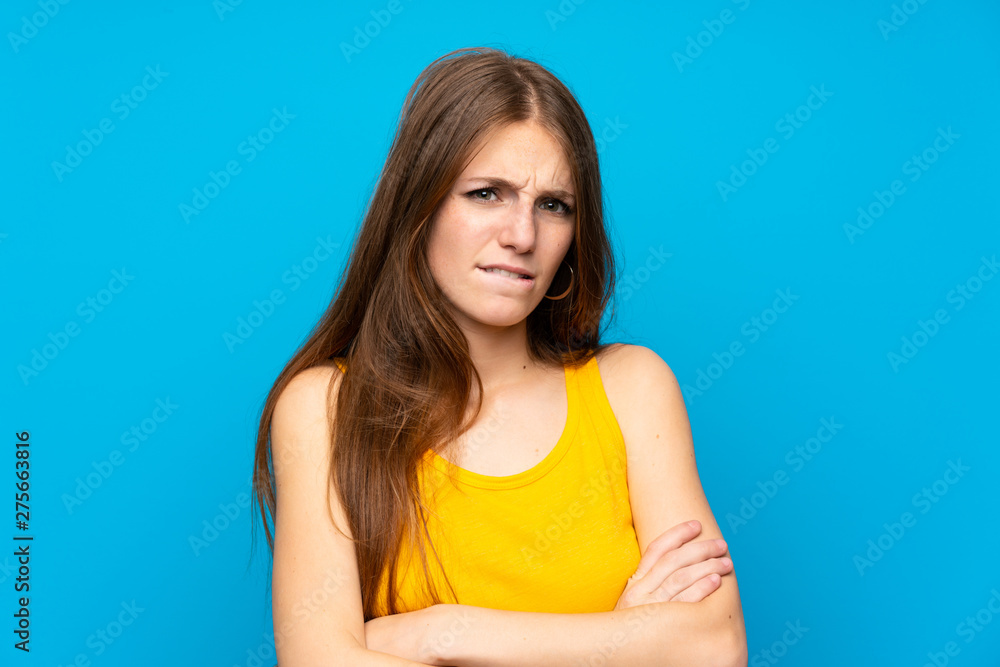 Young woman with long hair over isolated blue wall with confuse face expression Young woman with long hair over isolated blue wall with confuse face expression