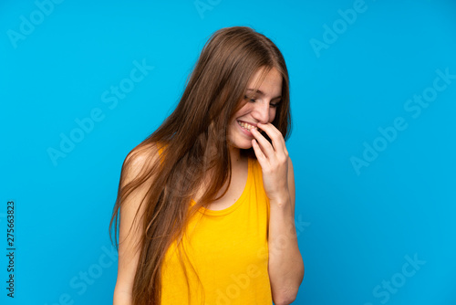 Young woman with long hair over isolated blue wall smiling a lot