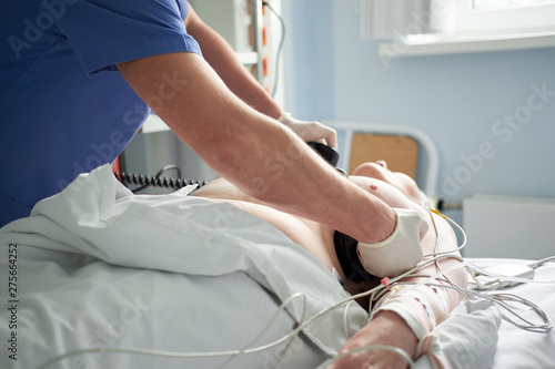 Doctor intensivist performs defibrillation to critical patient photo