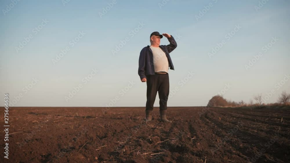 Adult farmer examining plowed field, preparing land for sowing. Seasonal agricultural works concept. Adult farmer examining plowed field, preparing land for sowing. Seasonal agricultural works concept.
