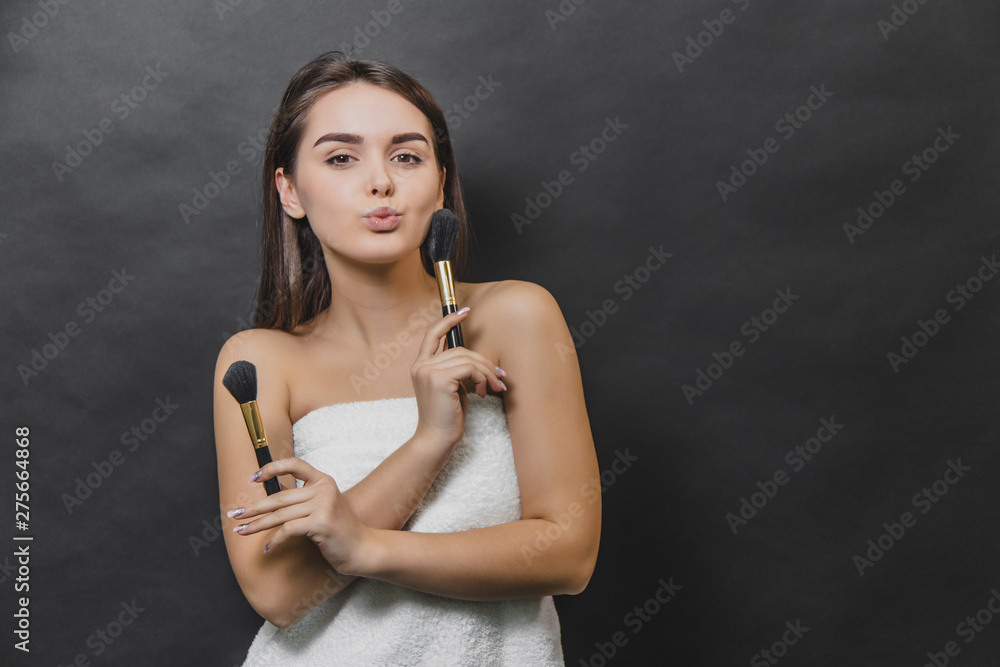 Beautiful young girl with two make up brushes in both hands. She is emitting kiss. Hands is s interlaced. Beautiful young girl with two make up brushes in both hands. She is emitting kiss. Hands is s interlaced.