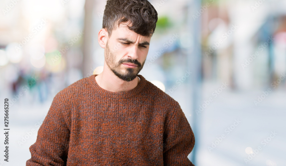 Young handsome man wearing winter sweater over isolated background with hand on stomach because nausea, painful disease feeling unwell. Ache concept. Young handsome man wearing winter sweater over isolated background with hand on stomach because nausea, painful disease feeling unwell. Ache concept.