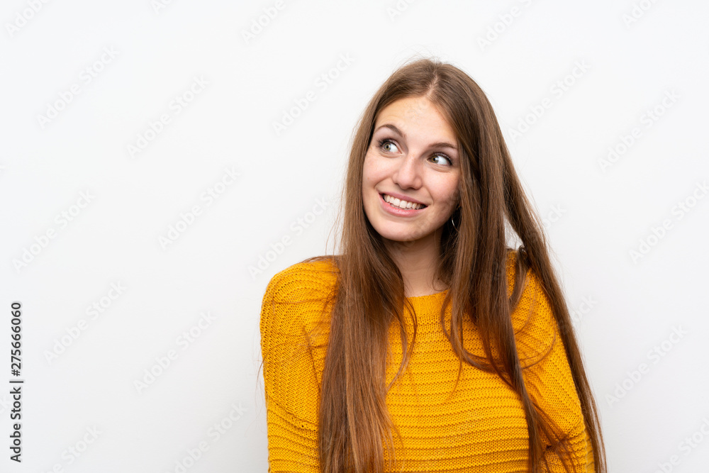 Young woman with yellow over isolated white wall laughing and looking up Young woman with yellow over isolated white wall laughing and looking up