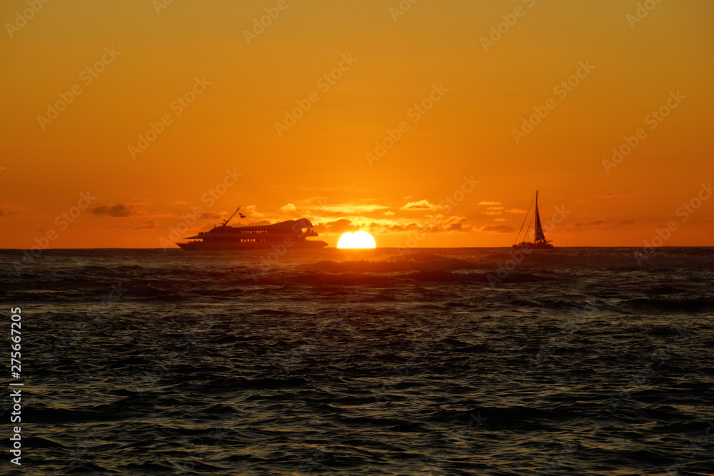 Sunset over the ocean with light reflecting on ocean waves moving with boats on the water in the distance